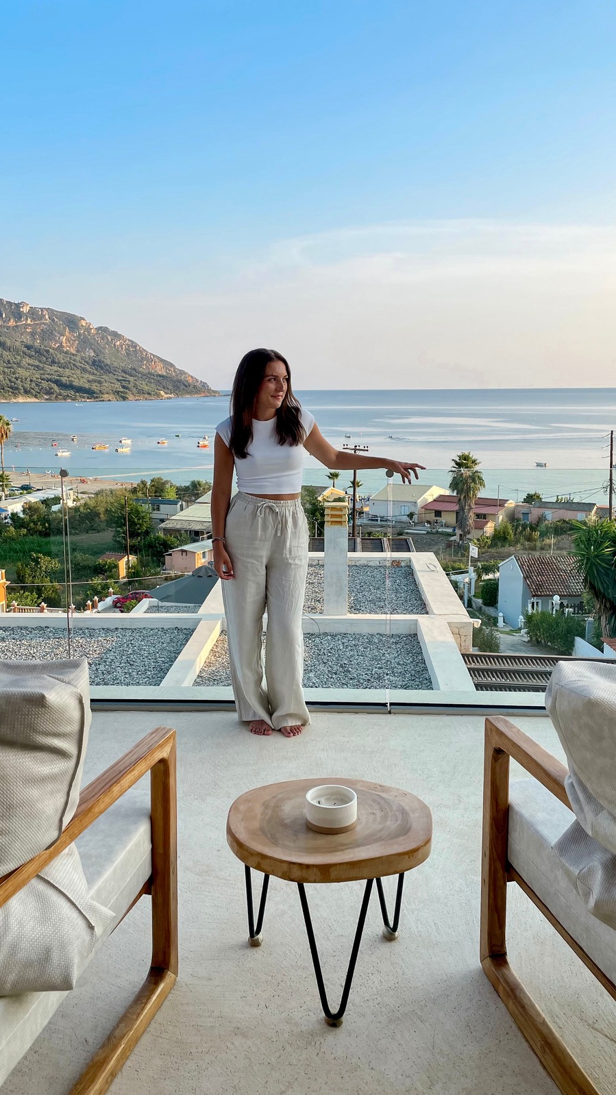 Klaudia enjoying a sunlit terrace overlooking the sea in Corfu